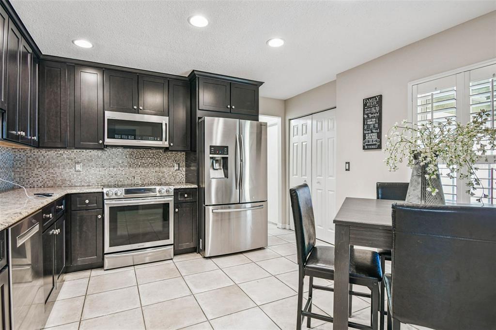 4161 Rolling Springs Drive Tampa, FL 33624 - Photo 6 of 52 a kitchen with granite countertop a refrigerator stove microwave and cabinets
