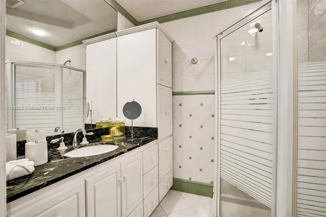 a bathroom with a granite countertop sink a mirror a vanity and a shower