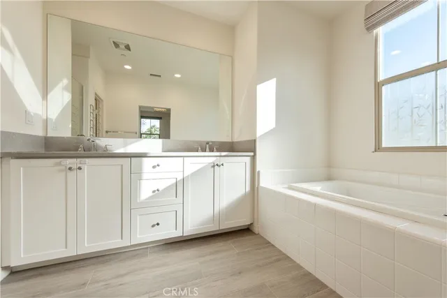 a spacious bathroom with a double vanity sink a mirror and a bathtub