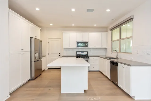 a large kitchen with stainless steel appliances kitchen island a large counter top and a sink