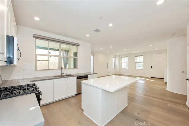 a large room with stainless steel appliances granite countertop a sink and dishwasher a stove with wooden floor