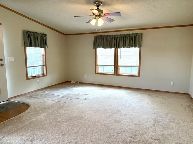 an empty room with windows and ceiling fan