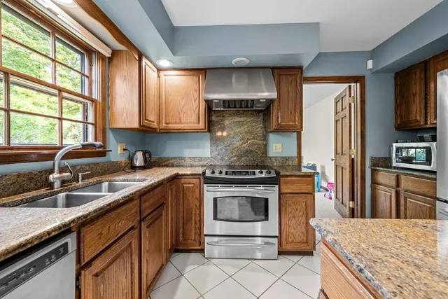 a kitchen with stainless steel appliances granite countertop a stove a sink and a microwave