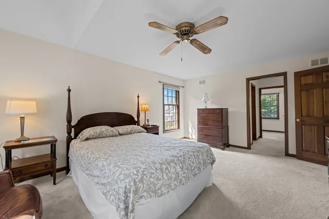 a spacious bedroom with a bed a dresser and a chandelier