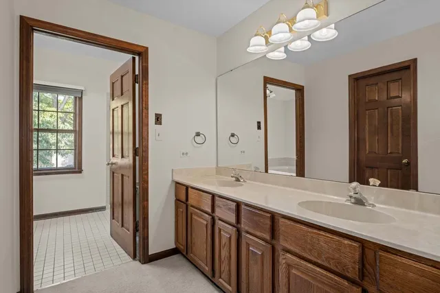 a bathroom with double vanity sinks a vanity a lamp and a mirror