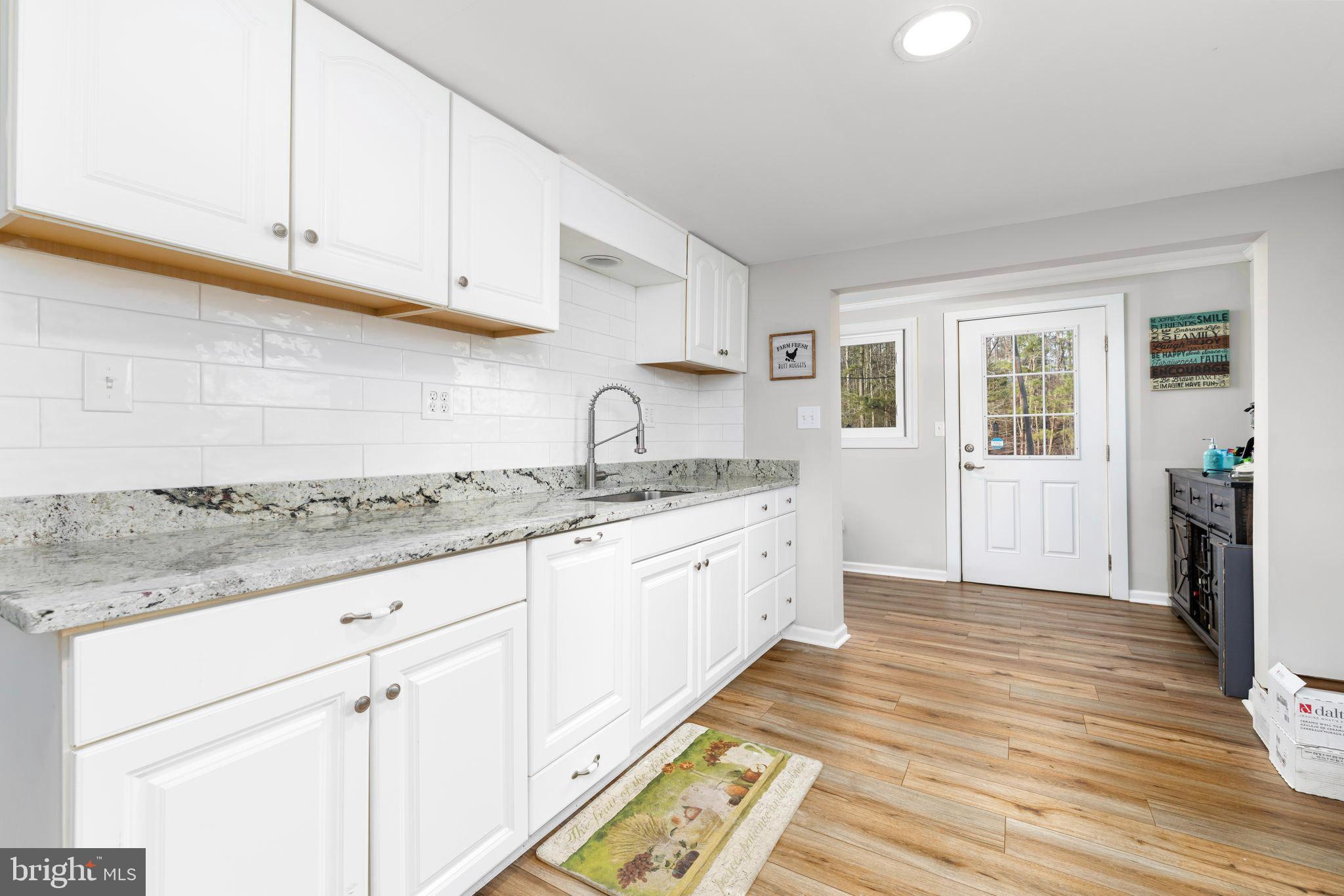 1052 South Hill Road Brodnax, VA 23920 - Photo 13 of 100 a kitchen with granite countertop white cabinets and wooden floor