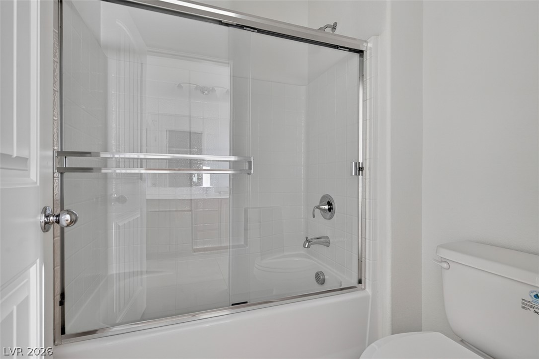 1100 East Sunset Road Henderson, NV 89011 - Photo 41 of 58 A well-maintained tub-shower combination features sleek glass sliding doors and bright white tiling.