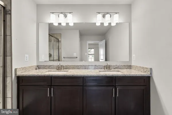 a bathroom with a granite countertop sink two large mirror and a