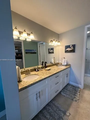a bathroom with a granite countertop double vanity sink and mirror