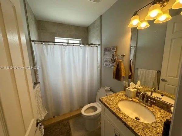 a bathroom with a granite countertop sink toilet and shower