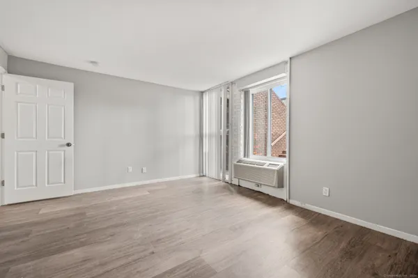 a view of an empty room with wooden floor and a window