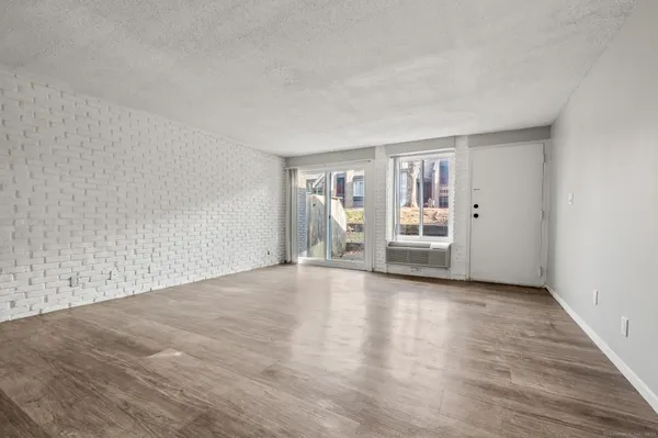 a view of an empty room with a window and wooden floor