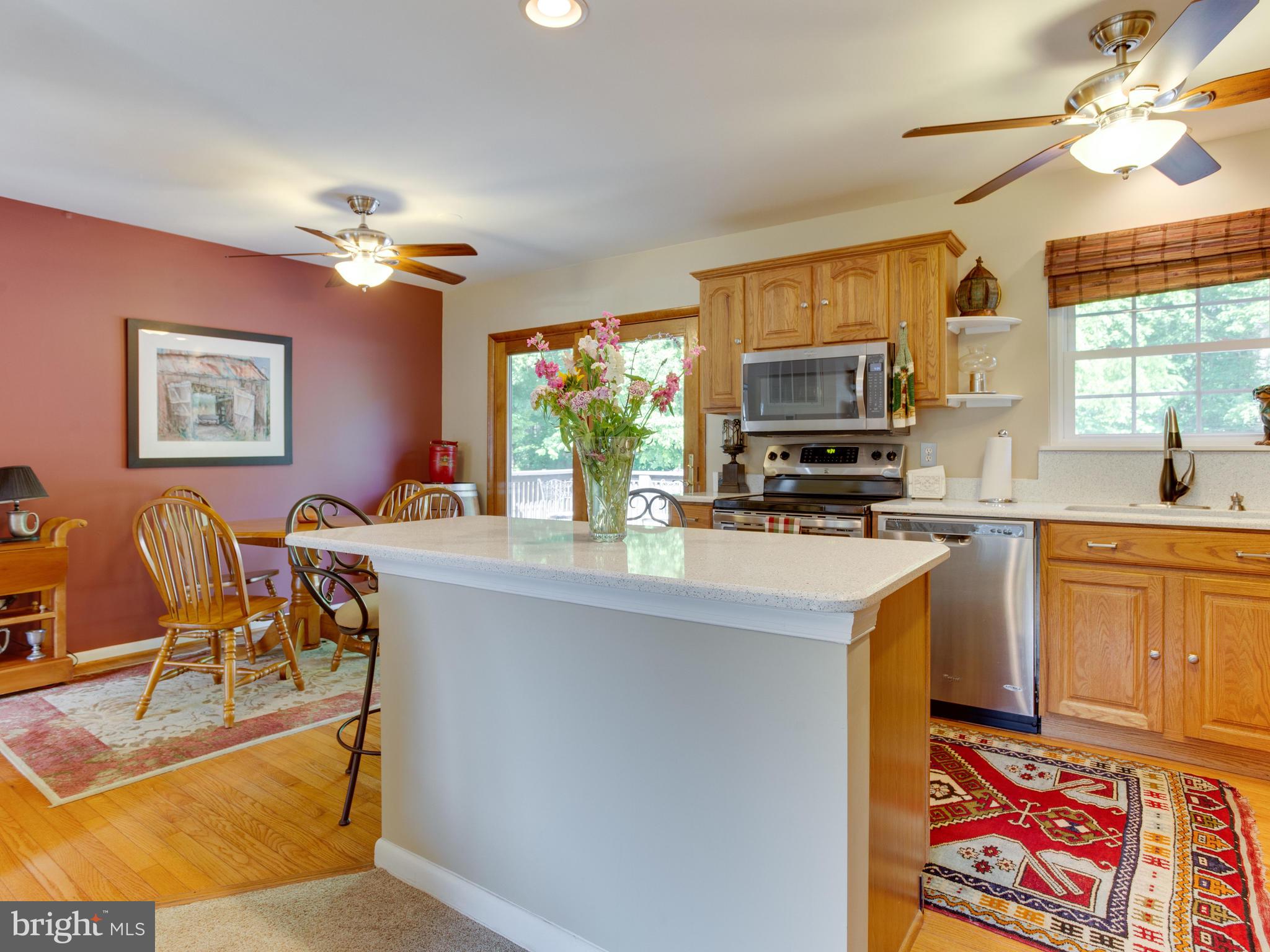 3100 Holland Cliffs Road Huntingtown, MD 20639 - Photo 7 of 44 a kitchen with stainless steel appliances granite countertop a stove top oven a sink a dining table and chairs with wooden floor