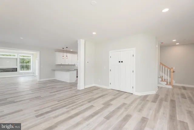 an empty room with wooden floor and kitchen view