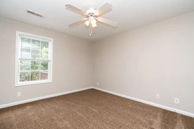 an empty room with a window and a fan