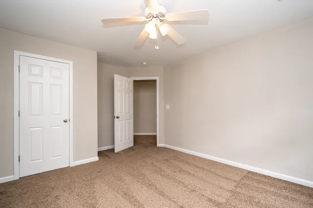 a view of an empty room and chandelier fan