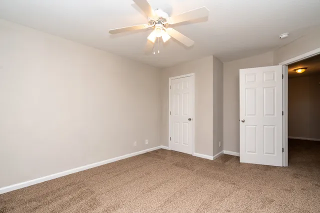 an empty room with a chandelier fan and closet