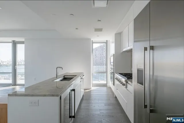a kitchen with a granite countertop counter top space a sink a refrigerator and windows
