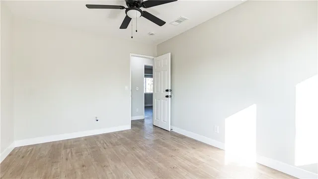 an empty room with ceiling fan and window