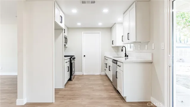 a kitchen with white cabinets and appliances