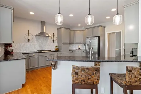a kitchen with stainless steel appliances granite countertop a stove a sink a refrigerator a center island a stove and a sink