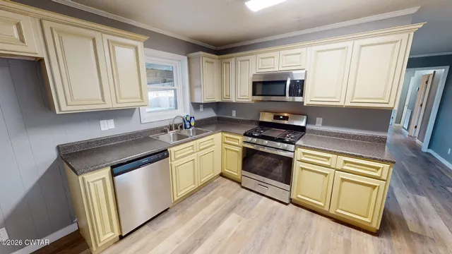 a kitchen with granite countertop a sink cabinets stainless steel appliances and a window