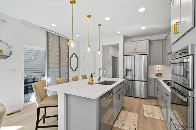 a kitchen with stainless steel appliances kitchen island granite countertop a table chairs in it and wooden floors