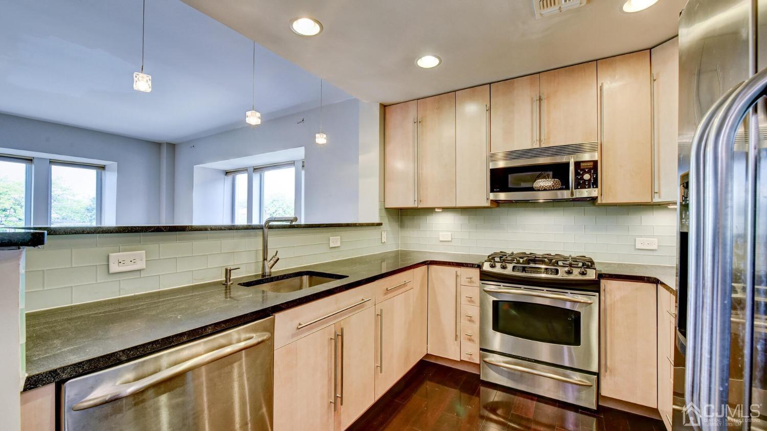 358 Rector Street, Unit 404 Perth Amboy, NJ 08861 - Photo 8 of 26 a kitchen with stainless steel appliances a stove a sink cabinets and a wooden floor