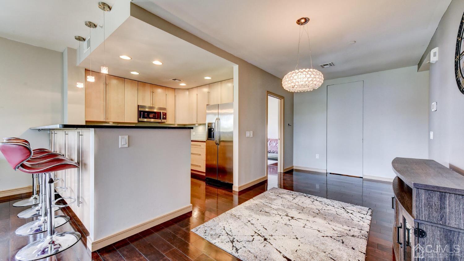 358 Rector Street, Unit 404 Perth Amboy, NJ 08861 - Photo 10 of 26 a kitchen with stainless steel appliances kitchen island granite countertop a table chairs in it and wooden floors