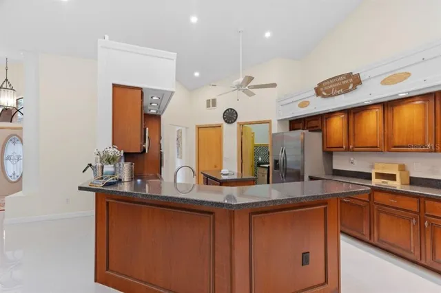 an empty room with wooden floor chandelier fan and windows