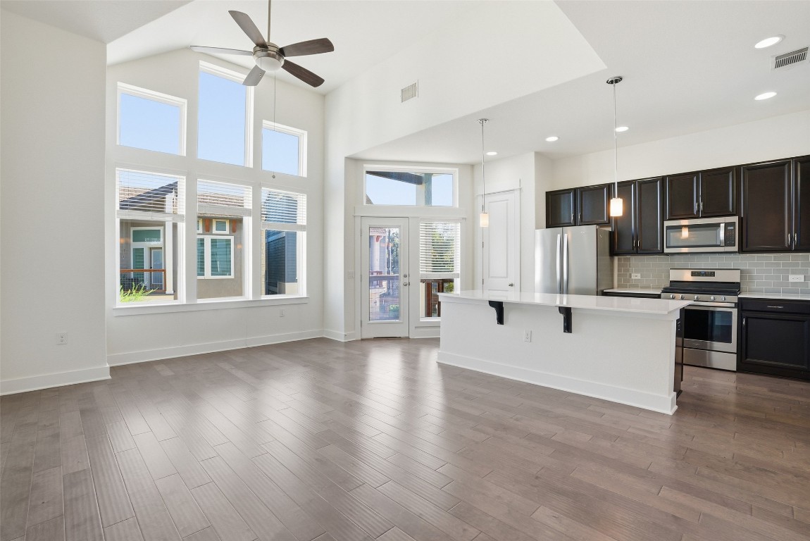 12604 Red Sparrow Street, Unit 14 Austin, TX 78729 - Photo 18 of 40 Kitchen featuring appliances with stainless steel finishes, pendant lighting, decorative backsplash, a center island, and a breakfast bar