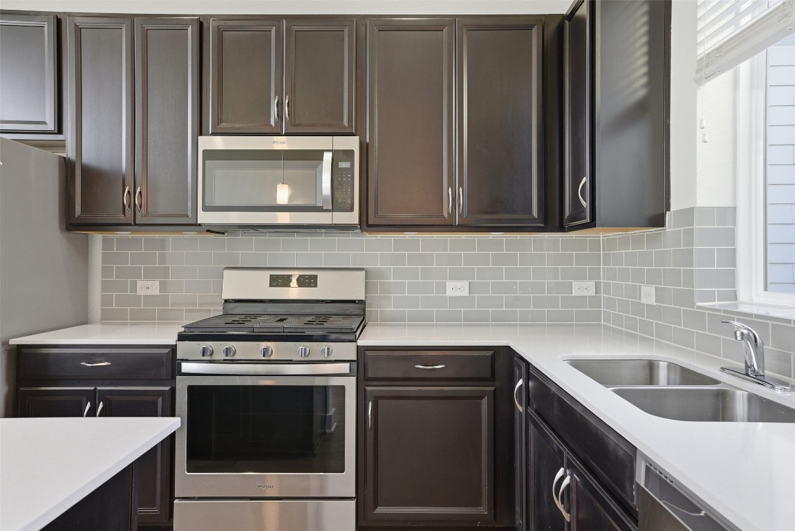 12604 Red Sparrow Street, Unit 14 Austin, TX 78729 - Photo 26 of 40 Kitchen with stainless steel appliances, dark brown cabinetry, light stone counters, and backsplash