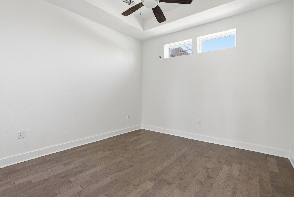 12604 Red Sparrow Street, Unit 14 Austin, TX 78729 - Photo 35 of 40 Empty room with dark wood finished floors, a ceiling fan, and a raised ceiling