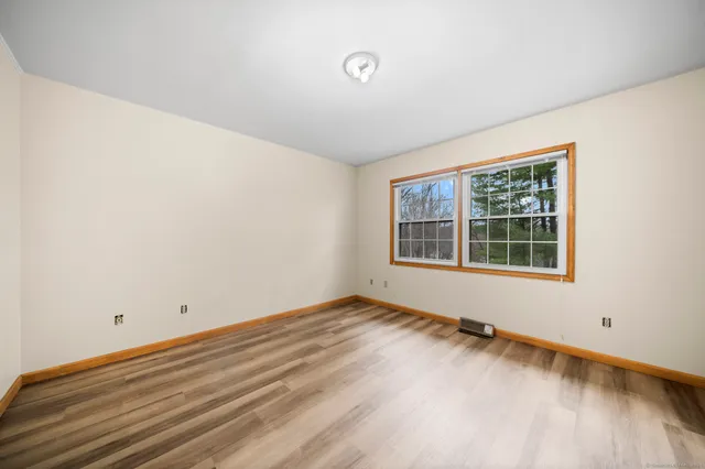 a view of an empty room with wooden floor and windows