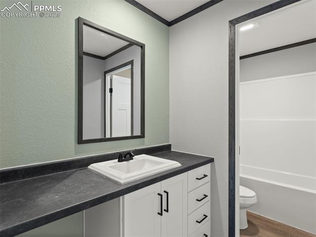 22843 Handle Road Calhan, CO 80808 - Photo 24 of 47 Bathroom with a textured wall, vanity, dark wood-style flooring, ornamental molding, and shower / bath combination