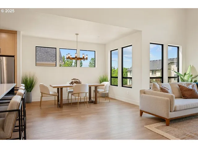 a kitchen with stainless steel appliances kitchen island granite countertop a dining table chairs and a refrigerator