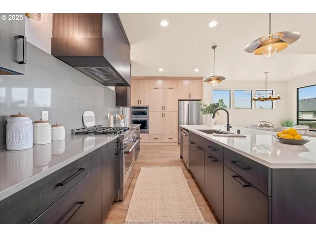 a kitchen with stainless steel appliances granite countertop a refrigerator a sink dishwasher a oven and white cabinets with wooden floor