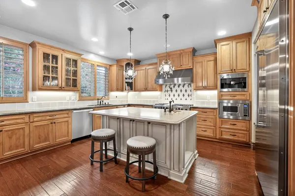 a kitchen with stainless steel appliances granite countertop a table chairs stove and sink