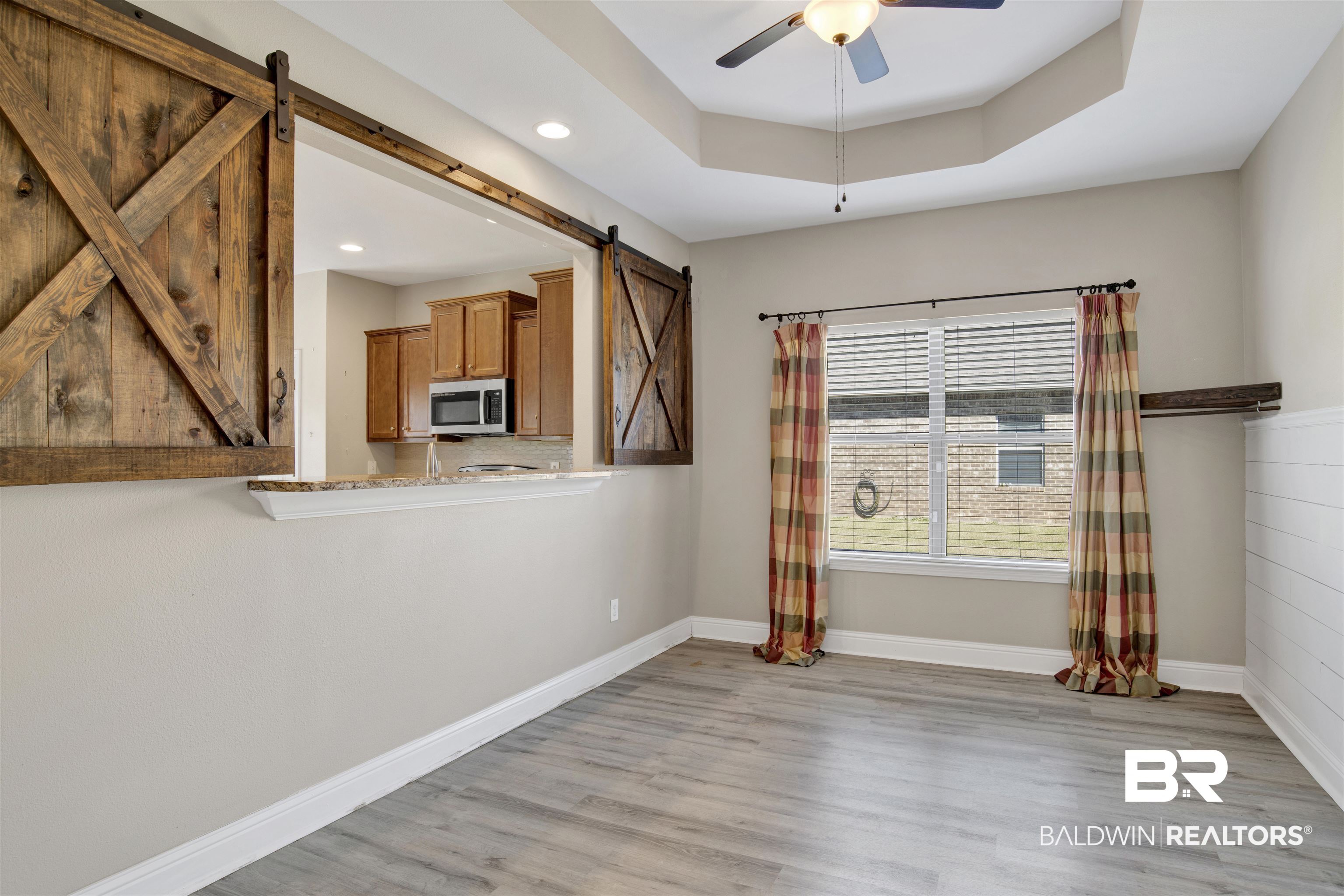24159 Tullamore Drive Daphne, AL 36526 - Photo 11 of 31 Empty room with ceiling fan, a tray ceiling, light hardwood / wood-style flooring, and a barn door