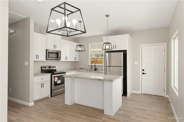 a kitchen with stainless steel appliances granite countertop white cabinets a refrigerator a stove a sink and dishwasher