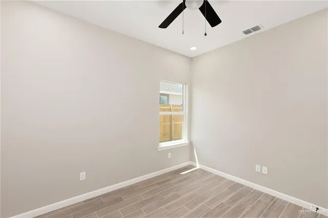 an empty room with a window and ceiling fan