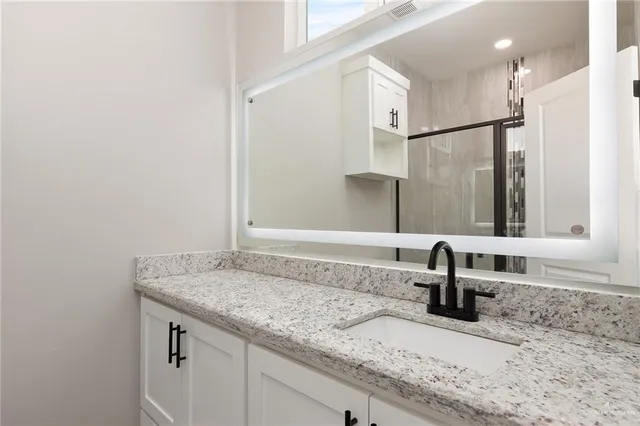a bathroom with a granite countertop sink and a mirror