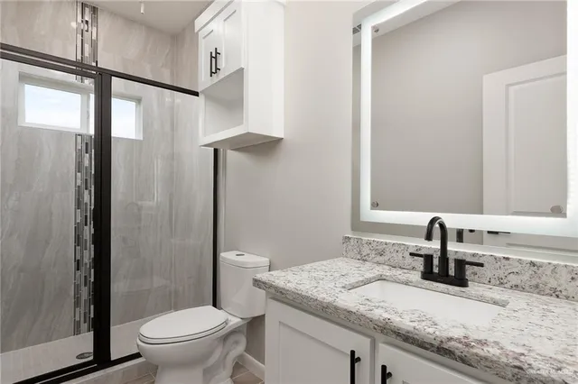 a bathroom with a granite countertop sink toilet and shower