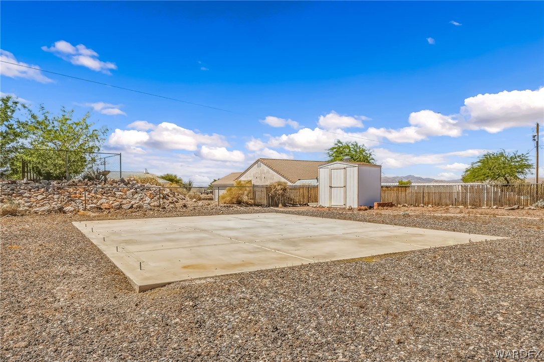 4088 Mercer Road Bullhead City, AZ 86429 - Photo 28 of 35 Property featuring a large concrete pad, gravel ground cover, and a detached storage shed