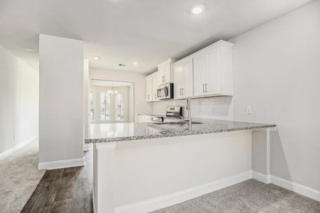 a kitchen with granite countertop a sink a stove and cabinets