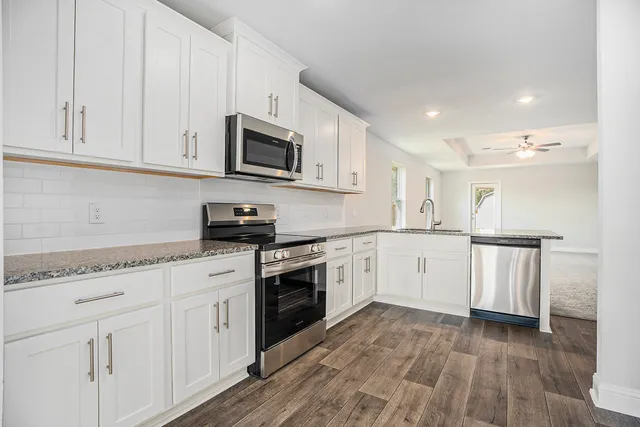 a kitchen with granite countertop white cabinets and white appliances