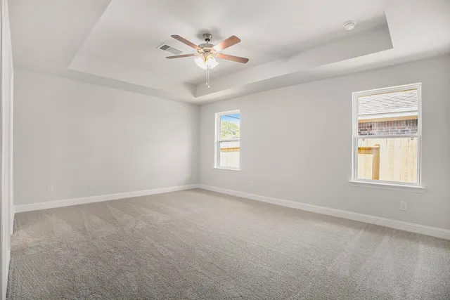 an empty room with windows and fan