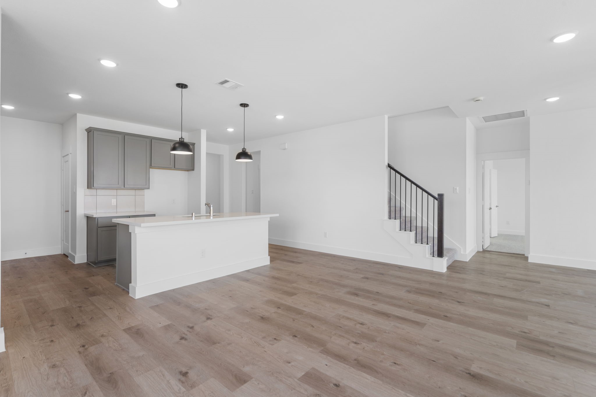 225 Sandhill Grv Trail Hempstead, TX 77445 - Photo 5 of 28 a view of an empty room with wooden floor and a kitchen