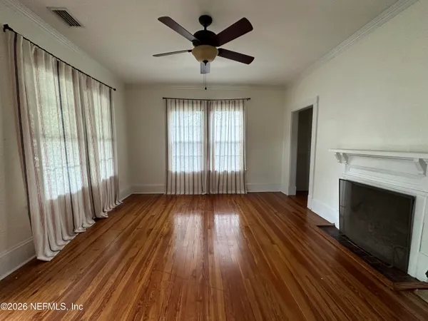 a view of an empty room with wooden floor and a window