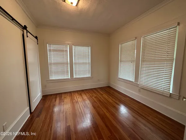a view of an empty room with wooden floor and a window